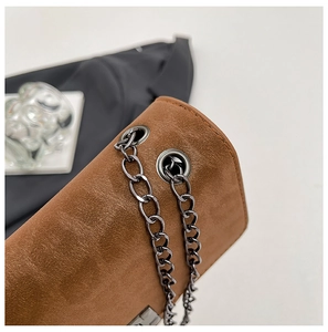 Detail of brown suede chain bag showing matte leather texture and dark metal eyelets