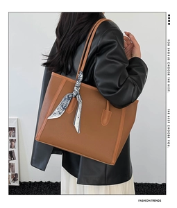 Gros plan du sac cabas en cuir marron avec un foulard en soie décoratif sur l'anse