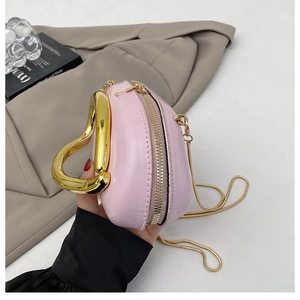 Detail of pink semi-circle handbag featuring chunky gold metal handle and chain strap