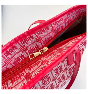 Macro view of red jacquard tote bag showing metal zipper and woven texture