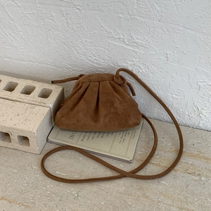 Borsa cloud in pelle scamosciata marrone su libro vintage con texture a pieghe