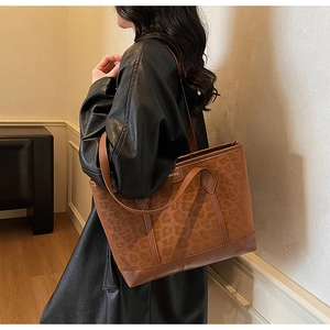 Close-up of leopard print tote bag with brown leather straps and fashion label