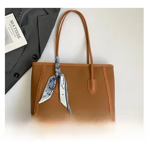 Close-up of brown tote bag with decorative scarf and elegant lychee grain texture