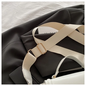 Detail of white leather shoulder bag with luxury gold buckle and woven strap