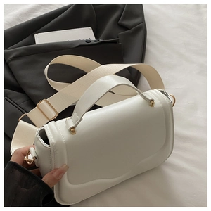 Detail of white leather shoulder bag featuring gold hardware and stylish woven strap