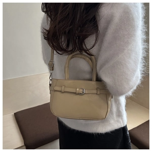 Detail of beige leather crossbody bag with decorative metal buckle and adjustable strap