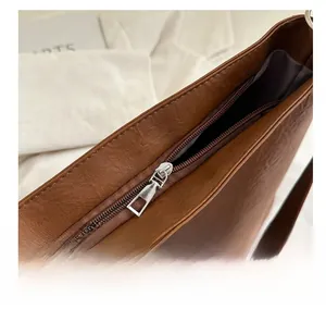 Detail of smooth silver metal zipper and dark brown leather texture on tote bag