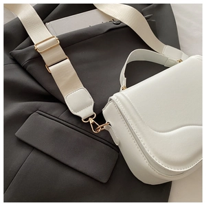 Close-up of white leather shoulder bag with textured flap and adjustable gold hardware buckle