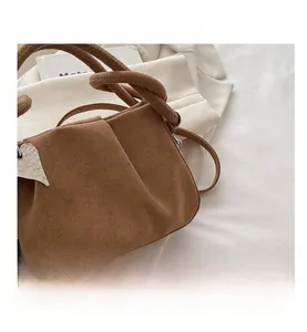 Dettaglio borsa in camoscio marrone con design a pieghe e fibbia a cuore in metallo argento
