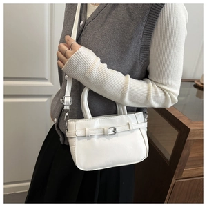 Close-up of white leather handbag with silver buckles and adjustable shoulder strap detail