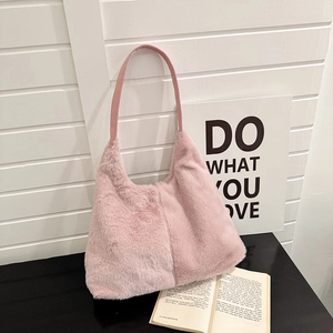 Borsa tote in ecopelliccia rosa con forma a trapezio e tracolla in pelle su un tavolo