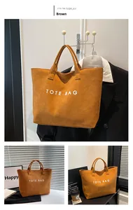 Detail view of large brown suede tote bag with white TOTE BAG lettering for daily commute