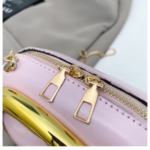 Pink leather shoulder bag detail with dual gold zippers and metallic round handle