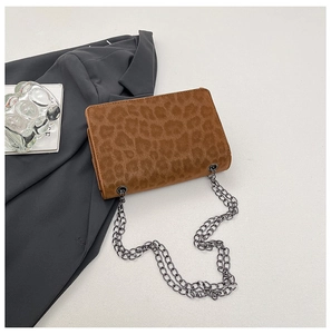 Detail of a brown leopard print chain bag with velvety texture on a grey suit background