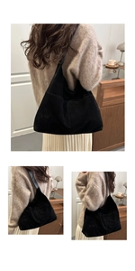 Detail of a large black suede tote bag with matte finish and wide shoulder strap