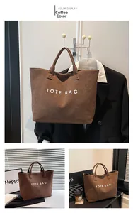 Detail of coffee brown suede tote bag with white TOTE BAG text and double handles