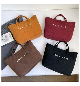 Detailed flat lay of suede tote bags in four colors with white TOTE BAG lettering detail