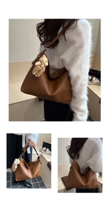 Detail of large dark brown leather tote bag featuring a cute teddy bear charm