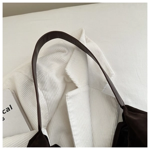 Close-up of matte dark brown shoulder bag with high-quality suede texture and leather strap