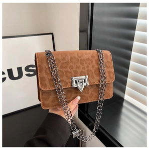 Macro detail of brown leopard print suede bag with dark metal chain strap and clasp