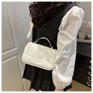 Detail of cream white PU leather crossbody bag with unique wavy flap and gold hardware