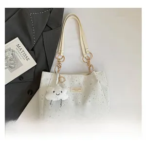 Detail of cream tote bag with star pattern, chain strap, and plush cloud charm