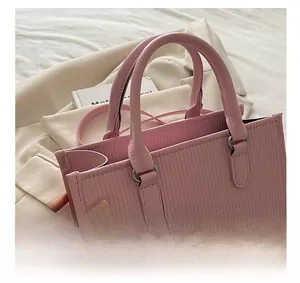 Dettaglio della borsa rosa con trama verticale, manici rotondi e fibbia argentata