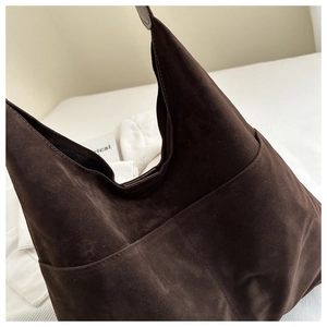 Detail view of large dark brown suede tote bag with contrast stitching and side pocket