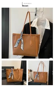 Détail d'un sac cabas marron avec motif litchi et foulard en soie décoratif