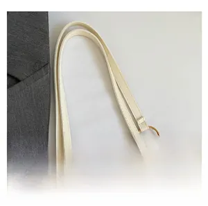 Detail of cream shoulder bag handle with elegant gold circular rings and metal chain link