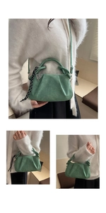 Detail of forest green pleated handbag with suede texture, scarf and heart pendant