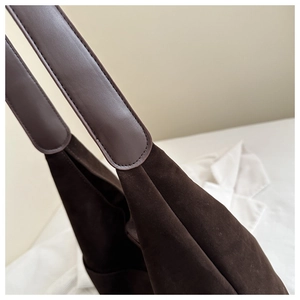 Detail of dark brown matte suede texture and leather handle stitching on tote bag