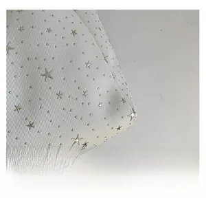 Detail of white twill fabric with silver star-shaped metal studs and micro rivets