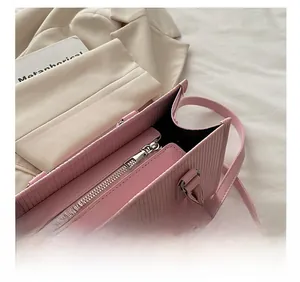 Dettaglio borsa rosa con cerniera fluida in metallo e pelle con goffratura verticale