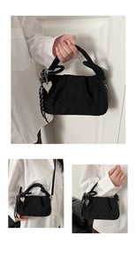 Detail of black suede-textured bag with heart pendant and striped rope decorative accent