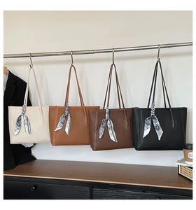 Macro detail of four textured leather tote bags in neutral tones with silk scarf accents