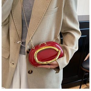 Detail of red patent leather shoulder bag with gold ring and metal chain strap