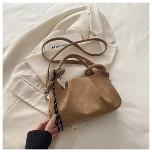 Detail of brown suede ruched bag with knot handle and silver heart pendant charm