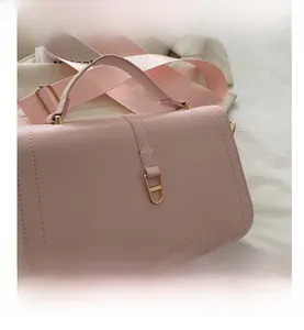 Dettaglio della borsa in ecopelle rosa con chiusura in metallo dorato e tracolla larga