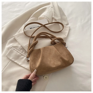 Macro shot of brown suede pleated handbag with knotted handle and shoulder strap detail