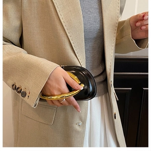 Chic black glossy leather clutch featuring a large designer gold circular metal handle