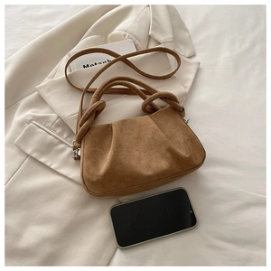 Macro view of brown suede pleated bag with size reference next to a mobile phone
