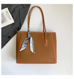 Détail du sac cabas en cuir marron à motif litchi avec un foulard décoratif en soie française
