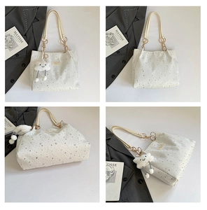 Detail of cream tote bag with silver star prints and white cloud plush charm