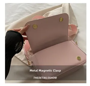 Dettaglio borsa rosa in pelle con chiusura magnetica e tracolla larga in tessuto