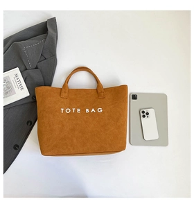 Flat lay of large brown faux suede tote bag with laptop and office accessories