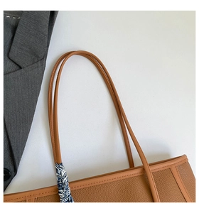 Détail d'un grand sac cabas en cuir marron avec foulard en soie élégant sur l'anse