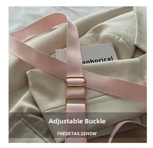 Dettaglio tracolla regolabile in nylon rosa con fibbia dorata su un blazer color crema