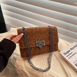 Brown leopard print crossbody bag with chain strap and metallic clasp on knit background