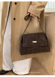 Dettaglio della borsa a tracolla retrò marrone scuro con fibbia in metallo e catena argento